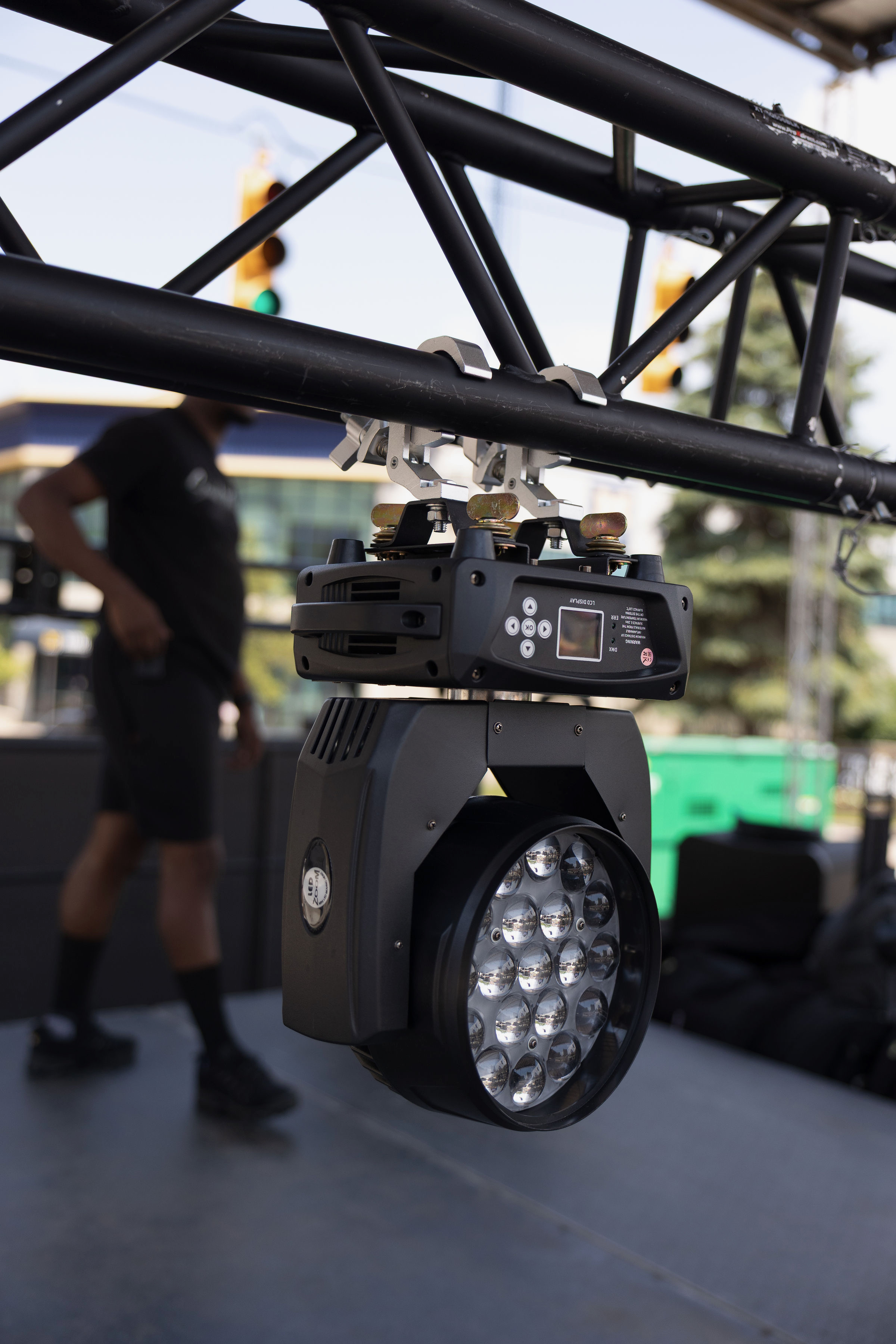 Moving light fixture on truss with crew member