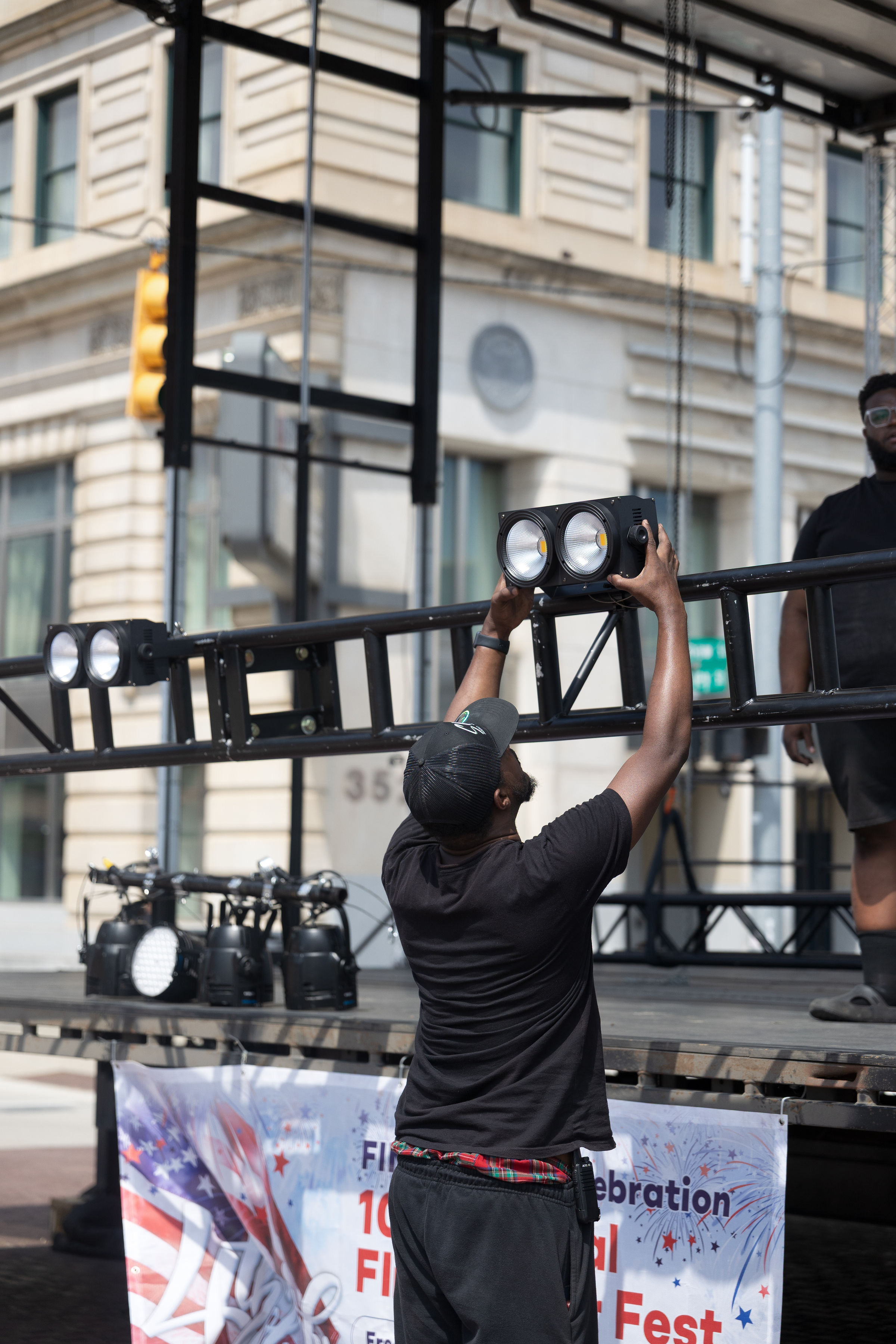 Crew member raising a light fixture up to the truss
